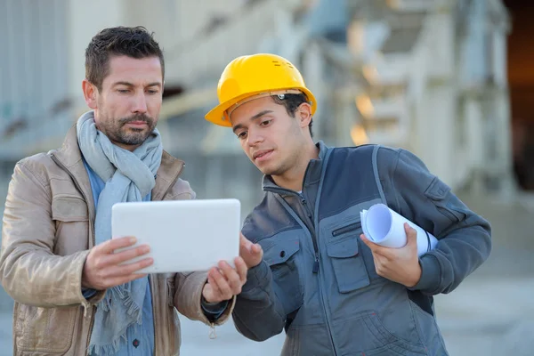 Konstruktören och manager arbetar på moderna tablett utanför renoverad fabrik — Stockfoto