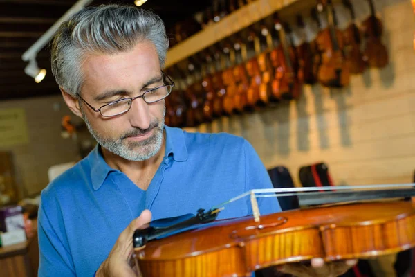 Homem de meia-idade positivo comprando violinos tradicionais na loja — Fotografia de Stock