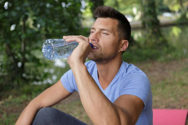 Aktiva mannen dricksvatten från en flaska som är utomhus — Stockfoto