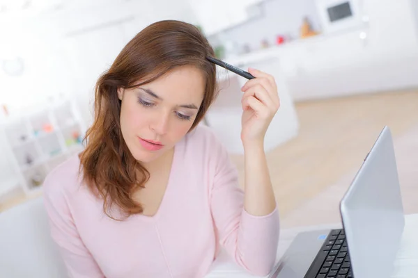 Mujer usando el ordenador portátil con la pluma mientras que mira algo —  Fotos de Stock