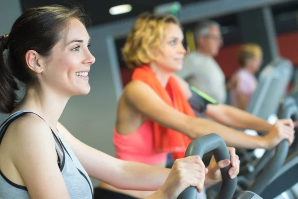 Grupo de mulheres andando de bicicleta de exercício no ginásio — Fotografia de Stock