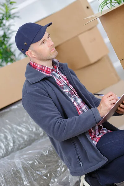 Kurier mit einem Klemmbrett im Hintergrund Pakete — Stockfoto