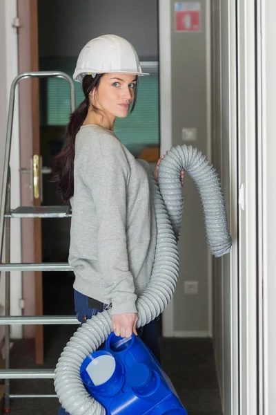 Kvinnliga entreprenör transporterar ventilation slang — Stockfoto