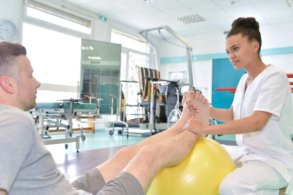 Male patient during physical therapy praxis and female physiotherapist — Stock Photo, Image