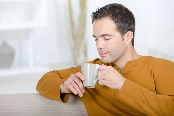 Homem feliz com xícara de chá dentro de casa no inverno — Fotografia de Stock