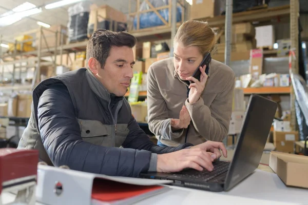 Travailleur d'entrepôt et gestionnaire regardant ordinateur portable dans un entrepôt — Photo