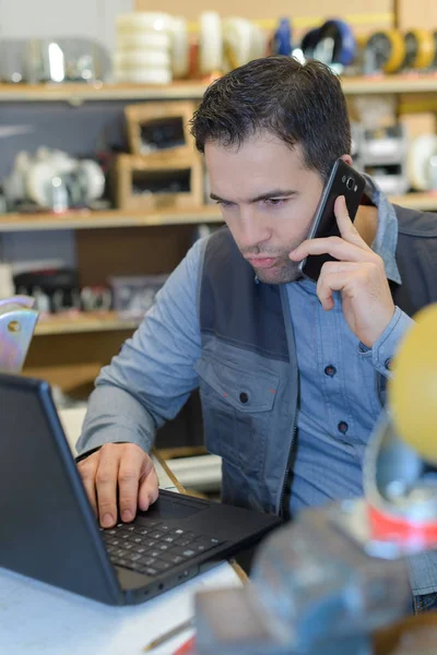 Gestionnaire d'entrepôt en utilisant le téléphone et l'ordinateur portable au bureau dans l'entrepôt — Photo