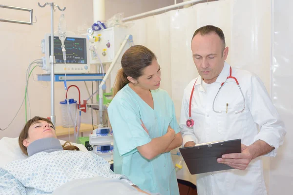 Physiothérapeute interagissant avec l'infirmière pendant que le patient est couché sur le lit — Photo