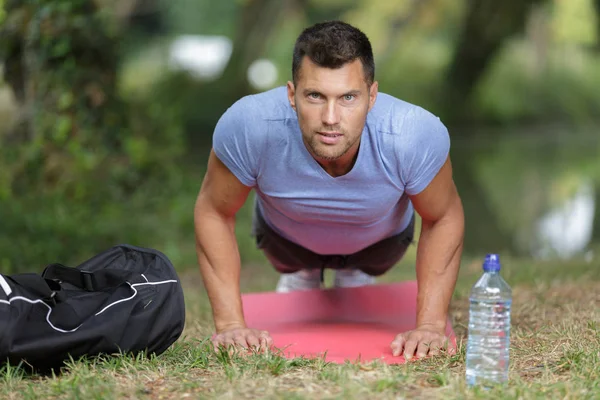 Muscular man push ups in a park — Stock Photo, Image