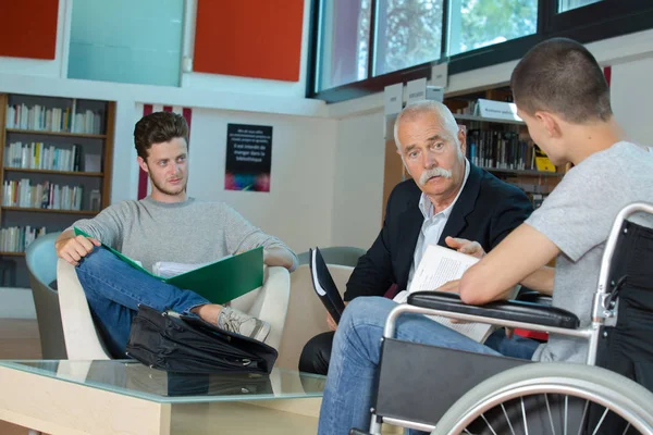 Student im Rollstuhl tippt in Bibliothek auf seinem Laptop — Stockfoto