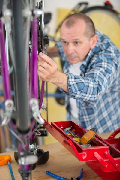 Mecânico serviceman ajustando engrenagem de bicicleta na roda na oficina — Fotografia de Stock