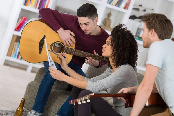 Gelukkige vrienden die gitaar spelen en thuis naar muziek luisteren — Stockfoto