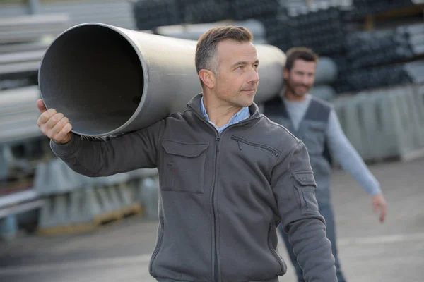 Trabalhadores que transportam tubo de borracha pvc flex pipe — Fotografia de Stock