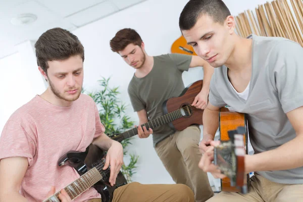 Amigos concentrados se divierten juntos tocando la guitarra — Foto de Stock