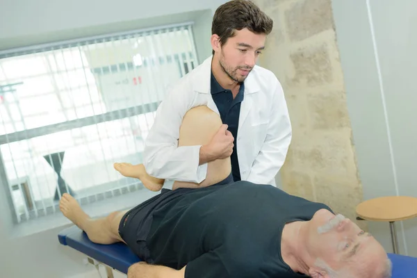 Arzt streckt bei Physiotherapie Bein aus — Stockfoto