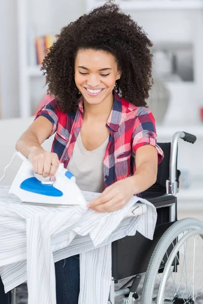 Donna sulla sedia a rotelle durante la stiratura a casa — Foto Stock