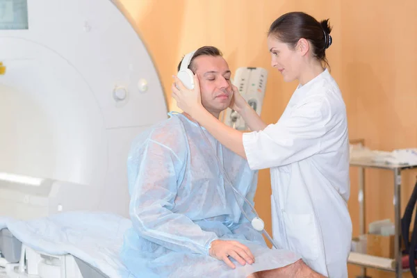 Рентгенолог надевает наушники на человека, проходящего МРТ — стоковое фото