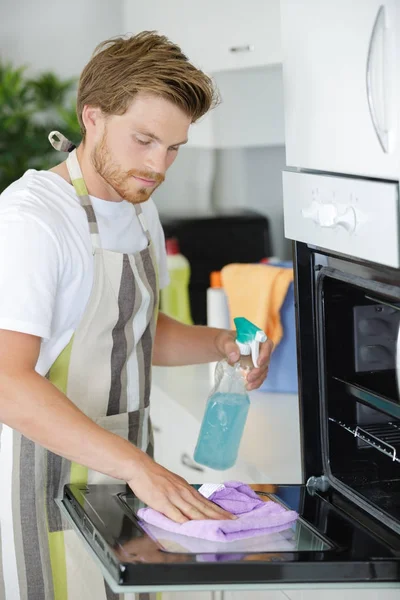 Mann putzt Backofen in der Küche — Stockfoto