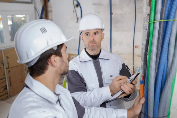 Byggare diskuterar om vatten rören i pannrummet — Stockfoto