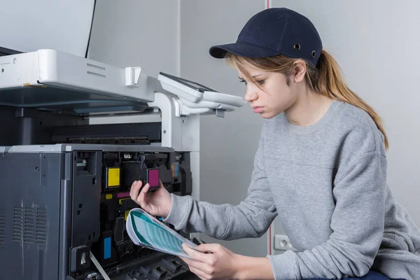 Jovem mulher fixando cartucho na máquina de fotocópia no escritório — Fotografia de Stock