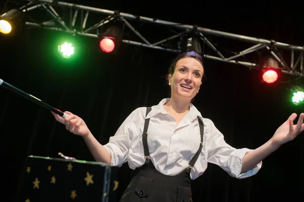 Female magician in suit showing trick with magic wand — Stock Photo, Image