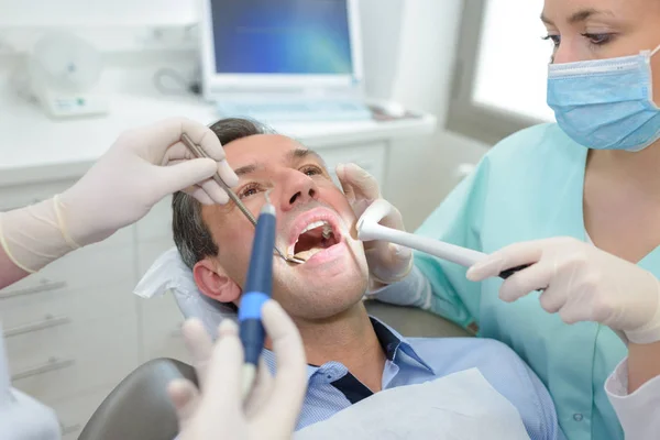 Жіночий стоматолог, що працює з пацієнтом в кабінеті стоматологічної клініки — стокове фото