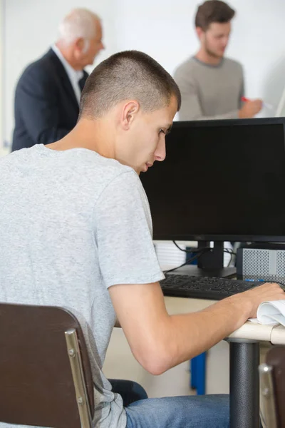 Profesor de informática asistiendo a un estudiante en el aula — Foto de Stock