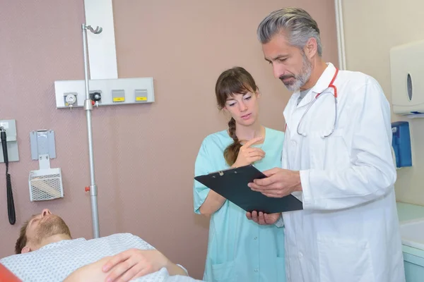 Médecin et infirmière avec presse-papiers visitant le patient à l'hôpital — Photo