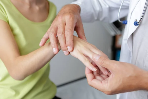 Arts controleren van vingers en pols van een patiënt — Stockfoto