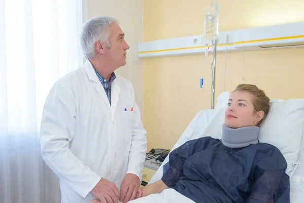 Male doctor examining a patient with cervical collar — Stock Photo, Image