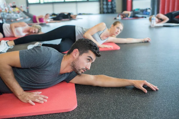 People laying down on mats in gym — Stock Photo, Image