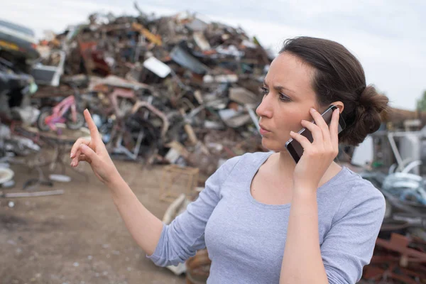 Lavoratori del riciclaggio dei metalli gesticolando e utilizzando il telefono cellulare presso discarica — Foto Stock