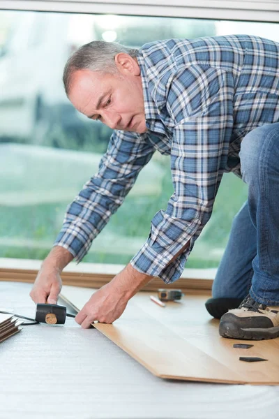 Carpenter lining parquet boards to each other fitting a plank — Stock Photo, Image