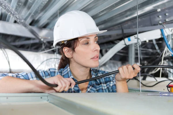 Arbeiterin überprüft Drähte und Kabel an der Decke — Stockfoto