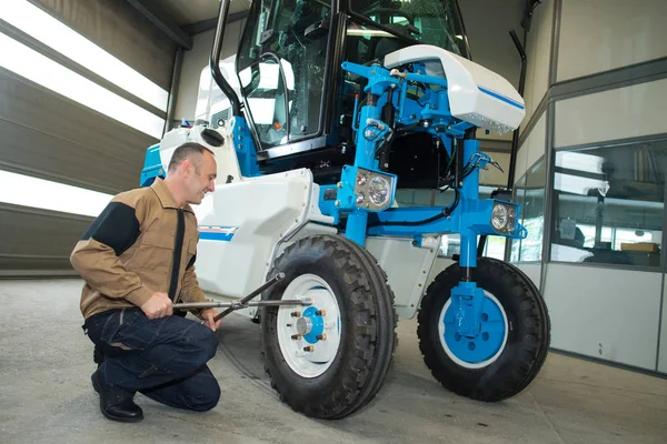 Hombre fijando un tractor en un hardware agroindustrial —  Fotos de Stock