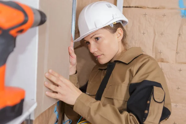 Kvinnlig ingenjör kontroll av nivån av en vägg — Stockfoto