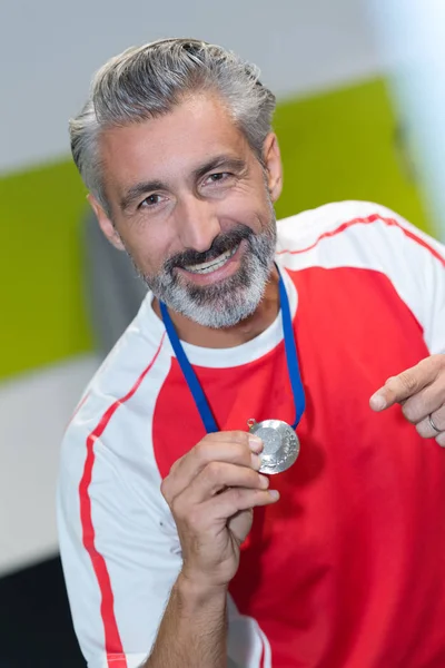 Μέση ηλικία κρατώντας ένα μετάλλιο ευτυχισμένη αθλητή — Φωτογραφία Αρχείου