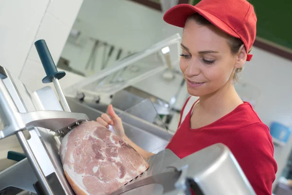 Mulher açougueiro de porco cortando presunto cozido com máquina — Fotografia de Stock