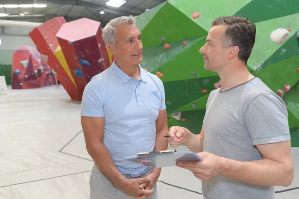 Due uomini in palestra di arrampicata discutendo il percorso — Foto Stock