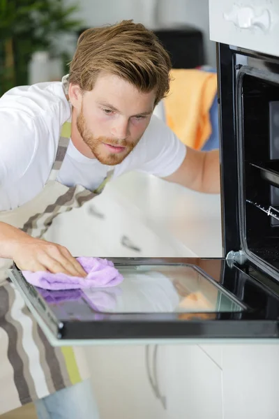 Hombre limpiando la puerta del horno — Foto de Stock