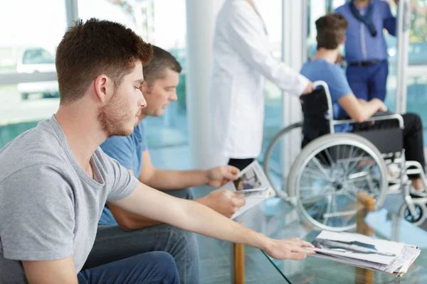 Hombres esperando en el vestíbulo de un hospital — Foto de Stock