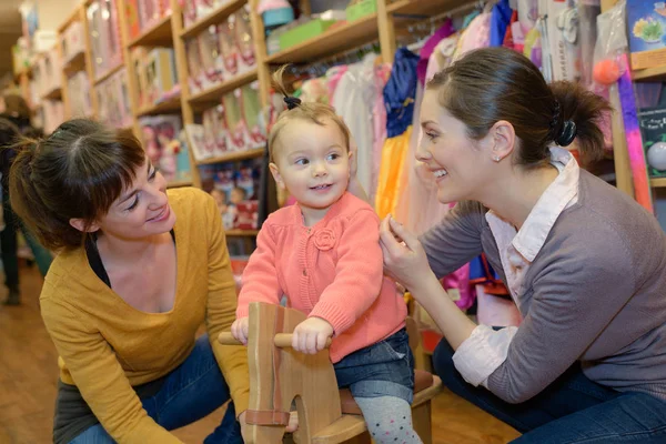 Mother and her friend shopping with daughter in toy store — Stock Photo, Image