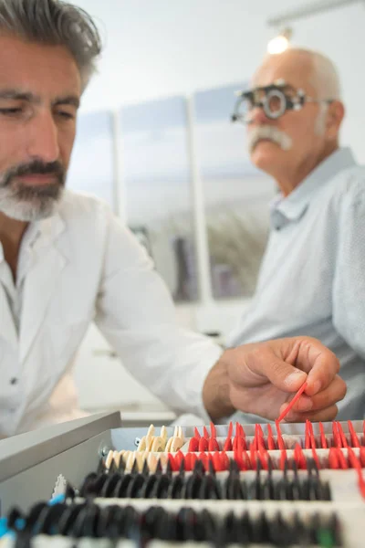 Optometrista maschio esaminando gli occhi dei pazienti anziani — Foto Stock