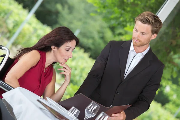 Waiter showing menu to woman in wheelchair — Stock Photo, Image