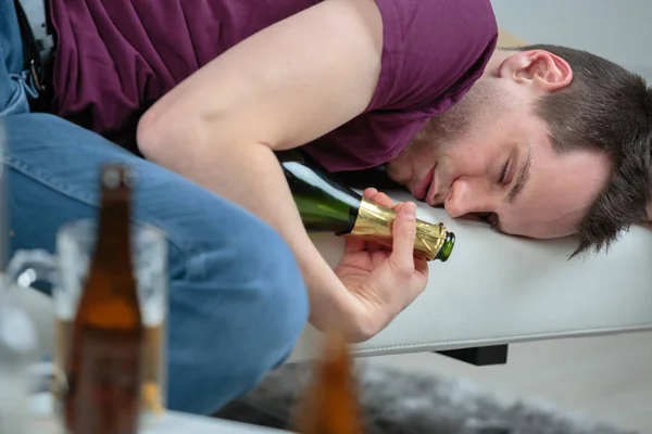 Inebriado hombre dormido sosteniendo vacía botella de vino — Foto de Stock