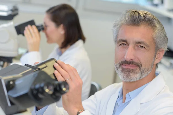 Zralý muž výzkumník pomocí mikroskopu v lékařské laboratoři — Stock fotografie