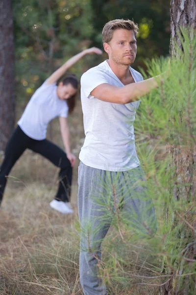 Couple stretching outdoors in the forest — Stock Photo, Image