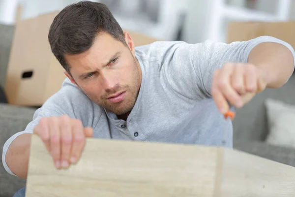 Mann tut sich schwer beim Zusammenbau der Möbel — Stockfoto