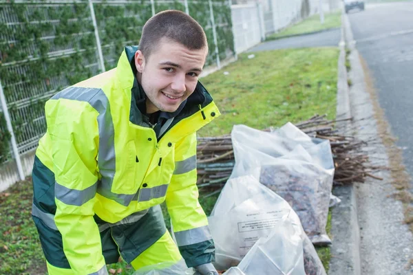 Young worker collects debris — Stock Photo, Image