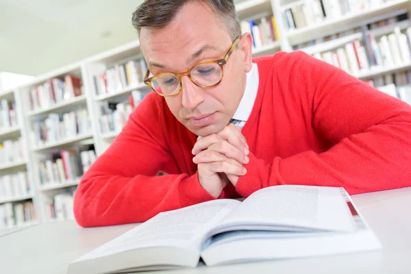 Man läser, hakan vilande på händerna — Stockfoto